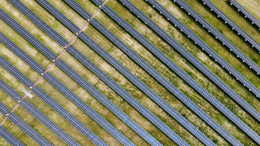 Aerial view of a utility-scale solar panel farm arranged in parallel rows across a green field — illustrative hero image for the SolarEdge IEEE 2030.5 Australia case study.
